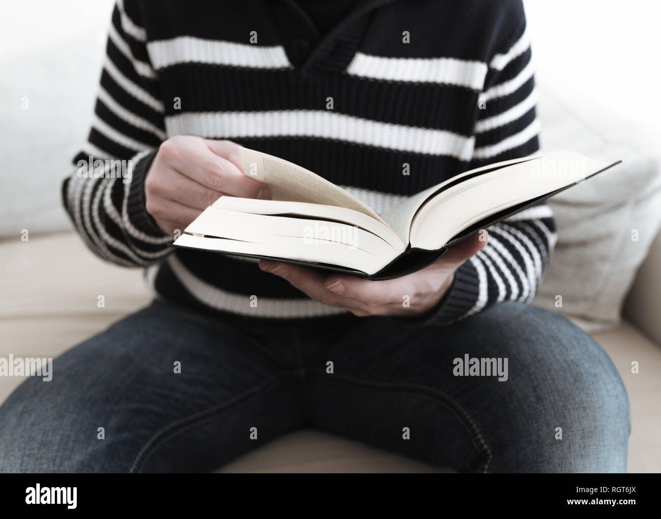 man sitting on sofa reading a book Stock Photo