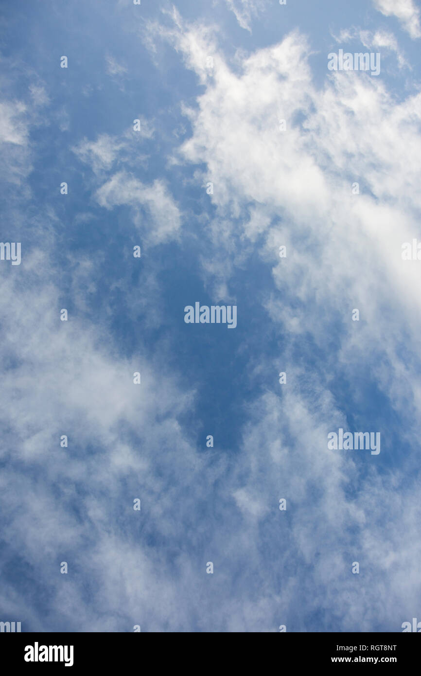 Bright Blue sunny sky with white fluffy clouds floating across on a ...
