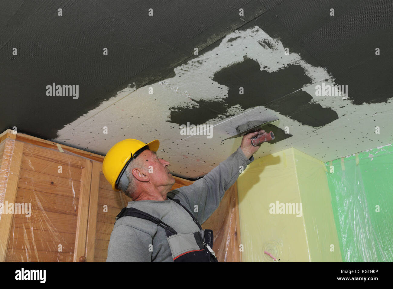 Worker Spreading Mortar Over Styrofoam Ceiling Insulation With