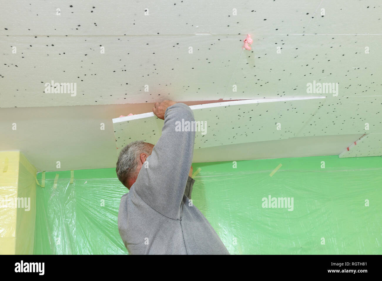 Worker Placing Styrofoam Insulation To Ceiling In A Room Indoor