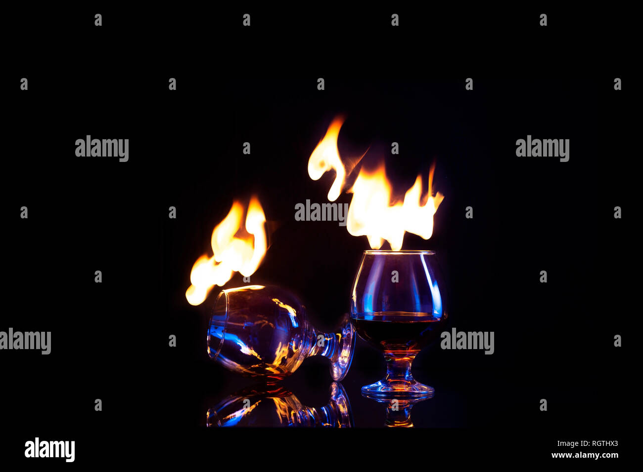 Glasses with burning alcohol on dark background Copy space Stock Photo