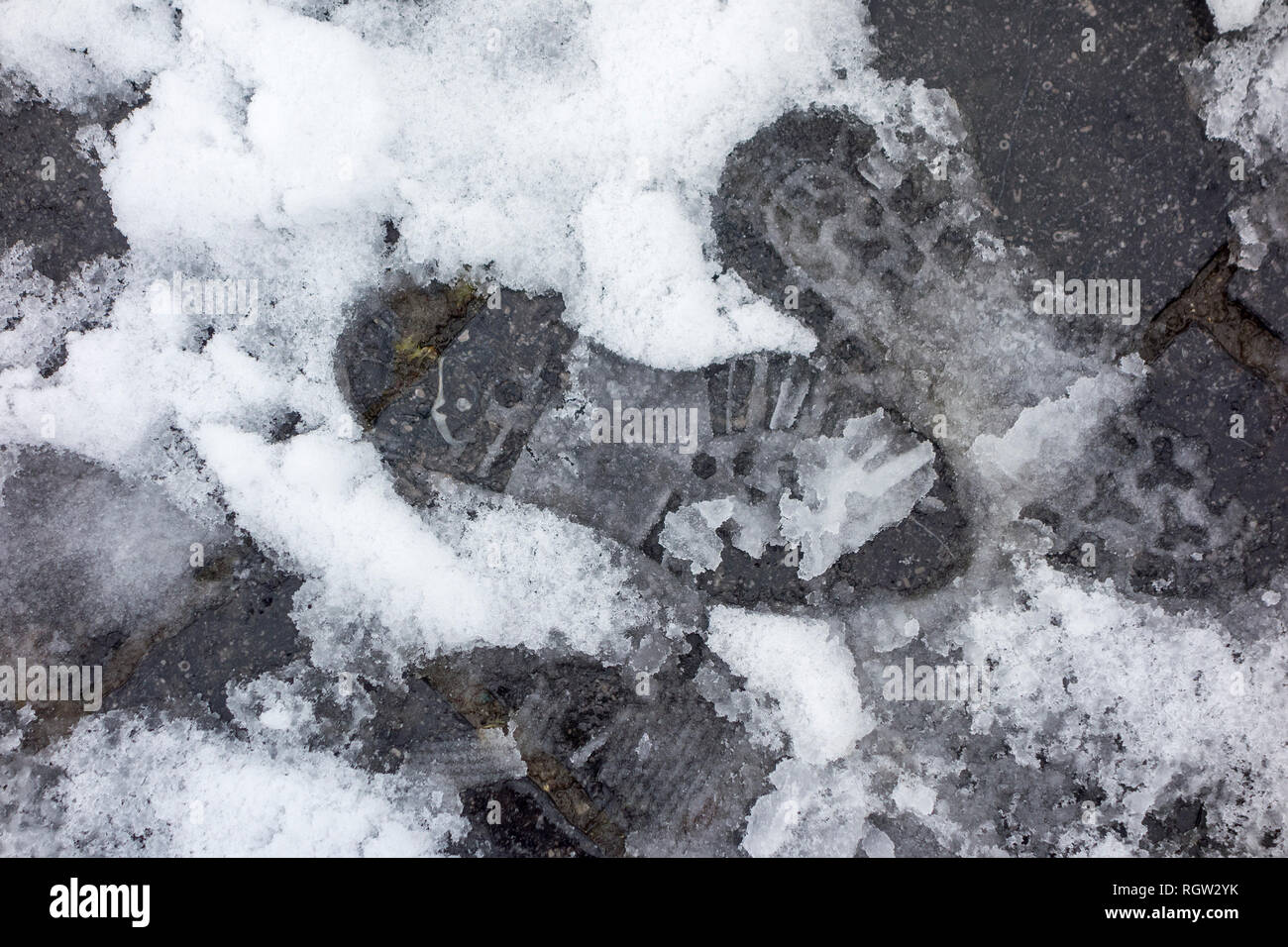Footprints of pedestrian in wet snow / sleet on slippery pavement / dangerous sidewalk in winter Stock Photo
