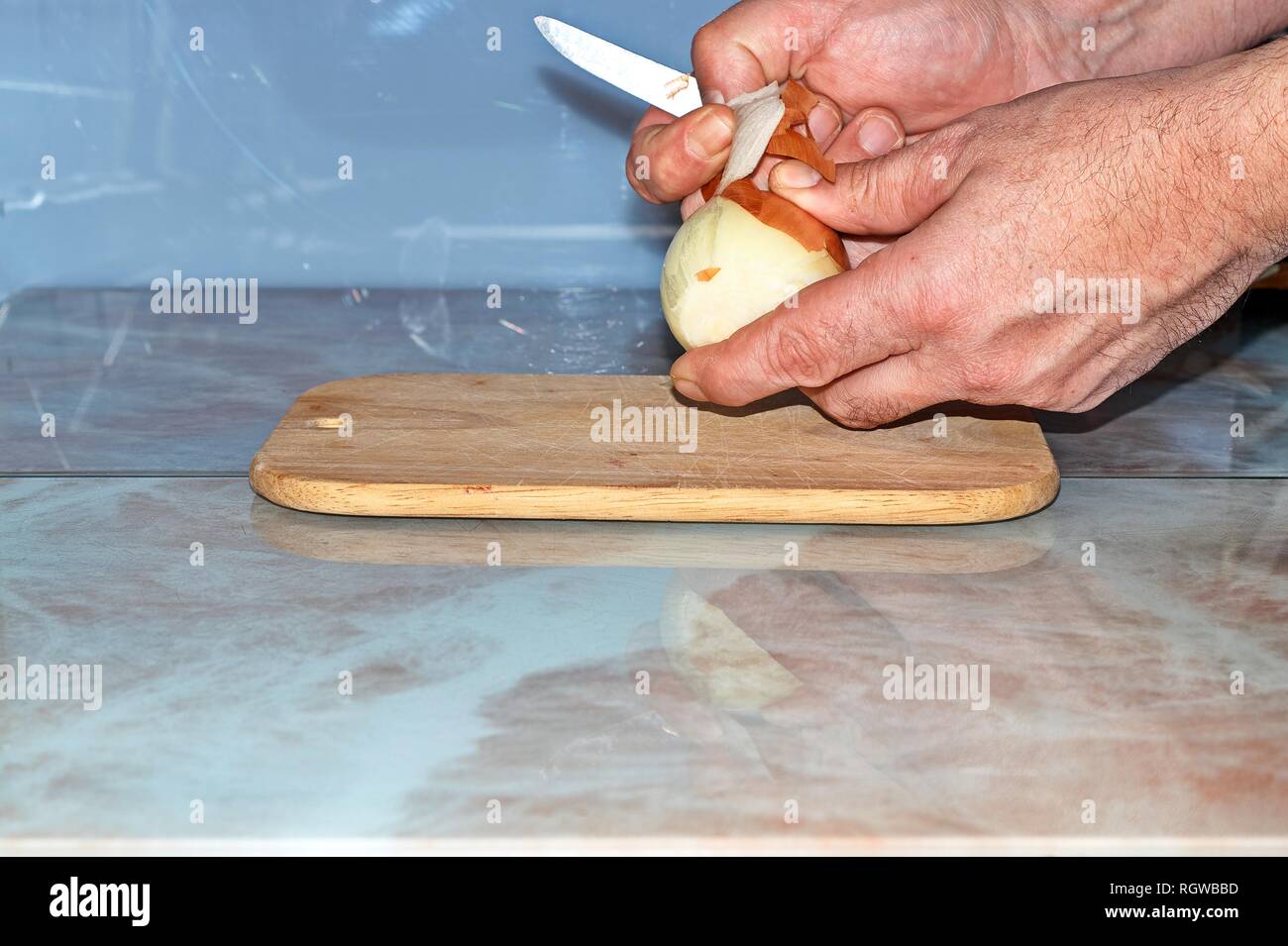 Chef slicing Onion, Allium cepa on the cutting board with a knife. Stock Photo