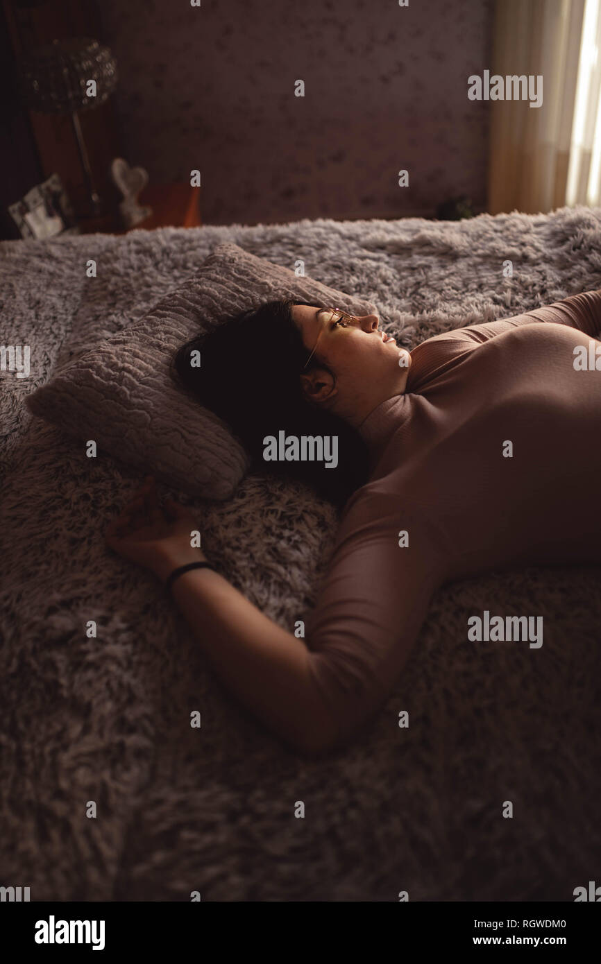 Young Woman lying on bed Stock Photo