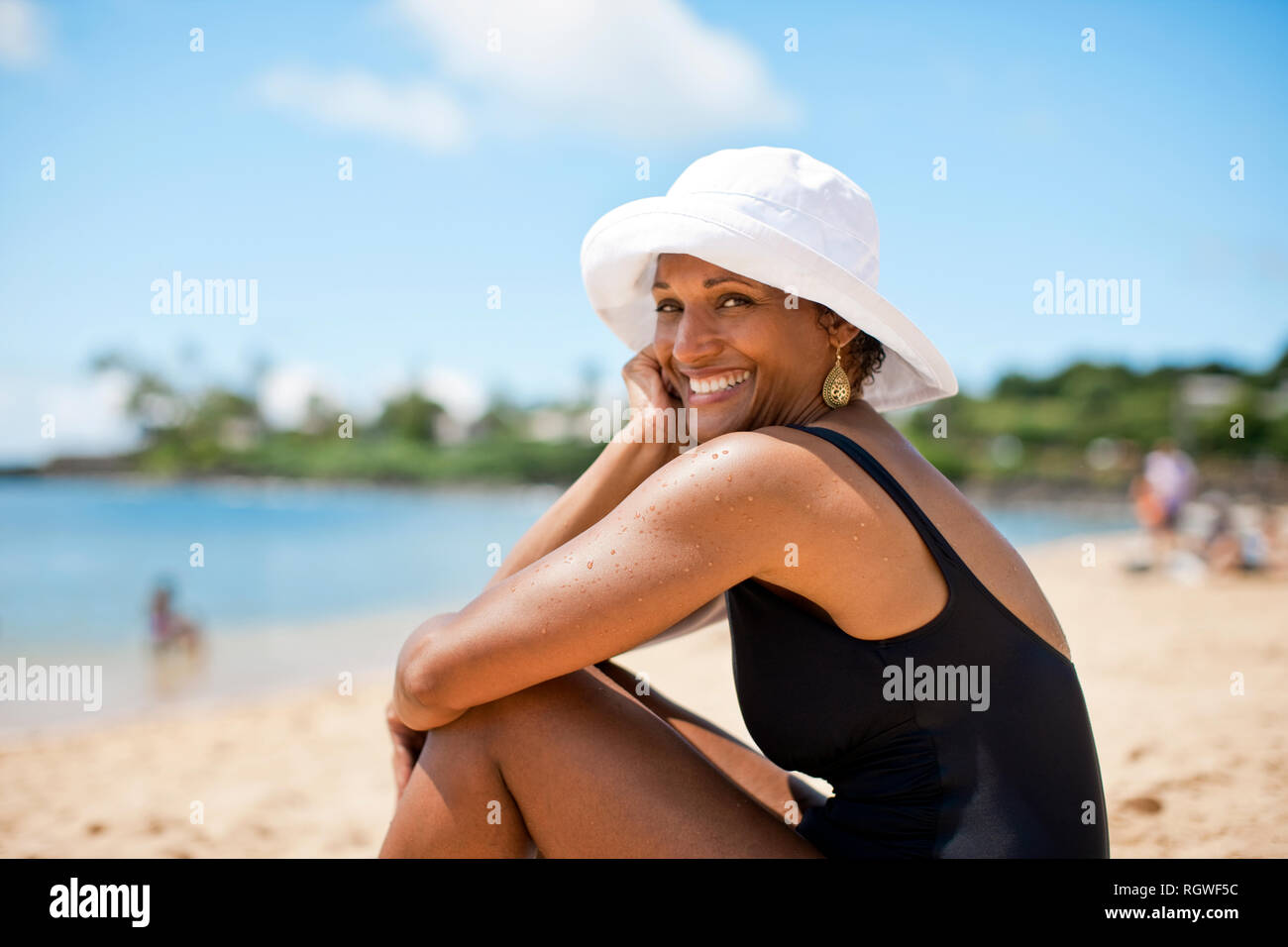 Portrait of woman sitting on beach Stock Photo - Alamy