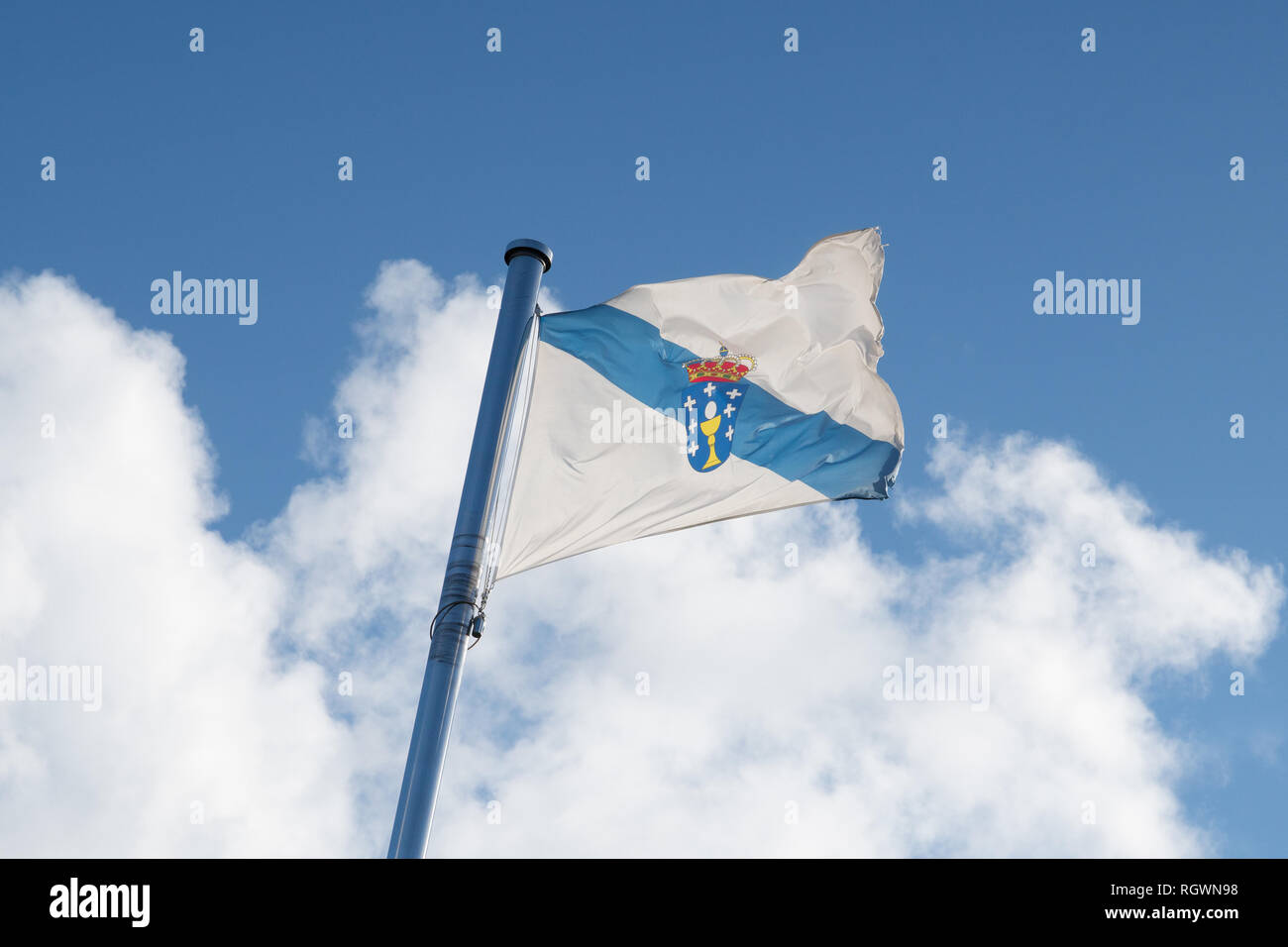 Flag of Galicia waving on the sky on cloudy sky Spain Stock Photo