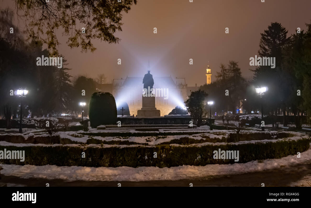 Evening scene outdoor in the main garden of Satu Mare with mysterious lights over Vasile Lucaciu statue, in winter season Stock Photo