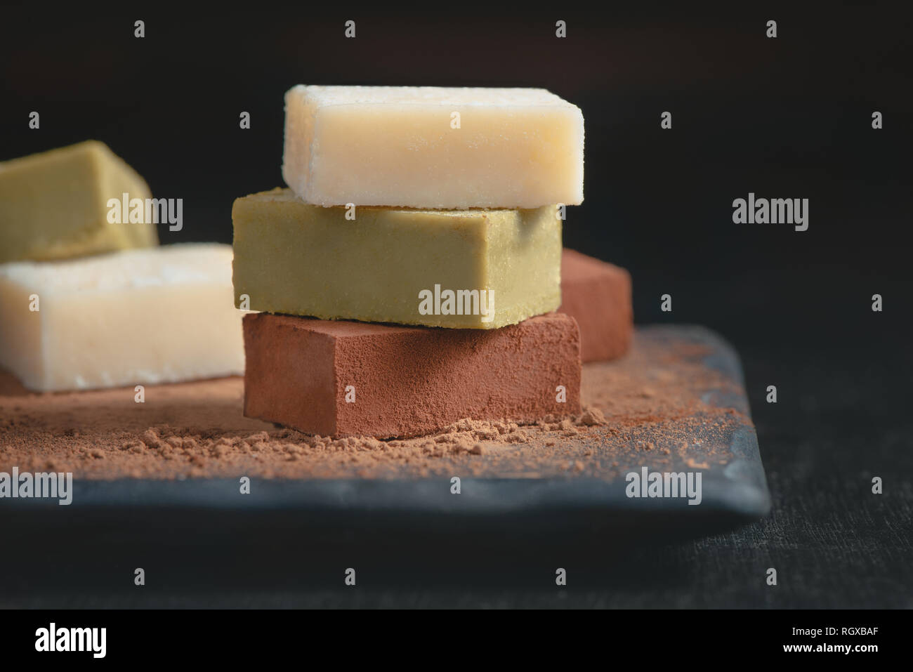 Assortment of soft chocolates on a black background with copy space. Milk and matcha Japanese gourmet chocolate close-up Stock Photo