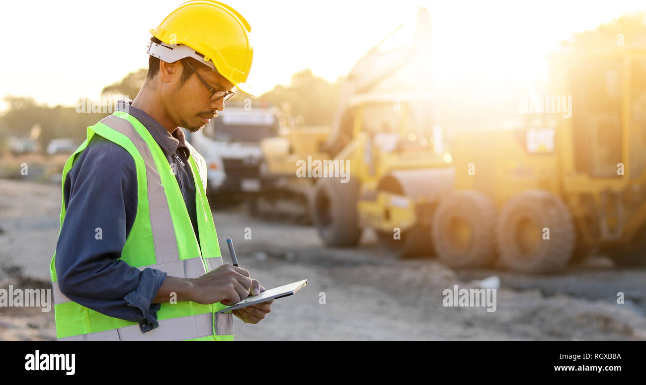 Asian engineer with hardhat using  tablet pc computer inspecting and working at construction site Stock Photo