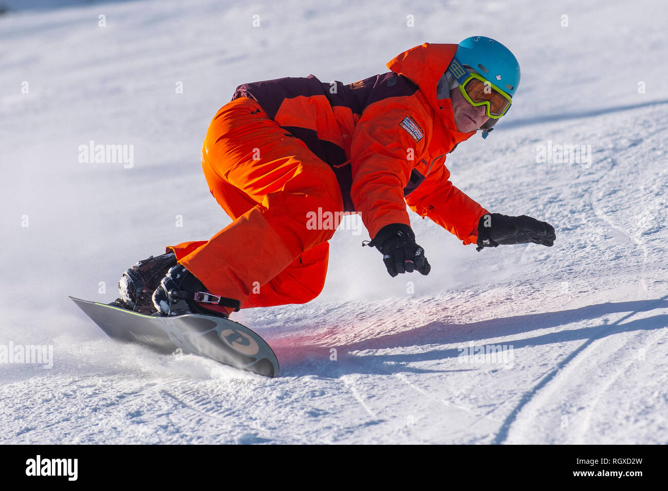 A male snowboarder carves a turn on piste in the French alpine resort of Courchevel. Stock Photo