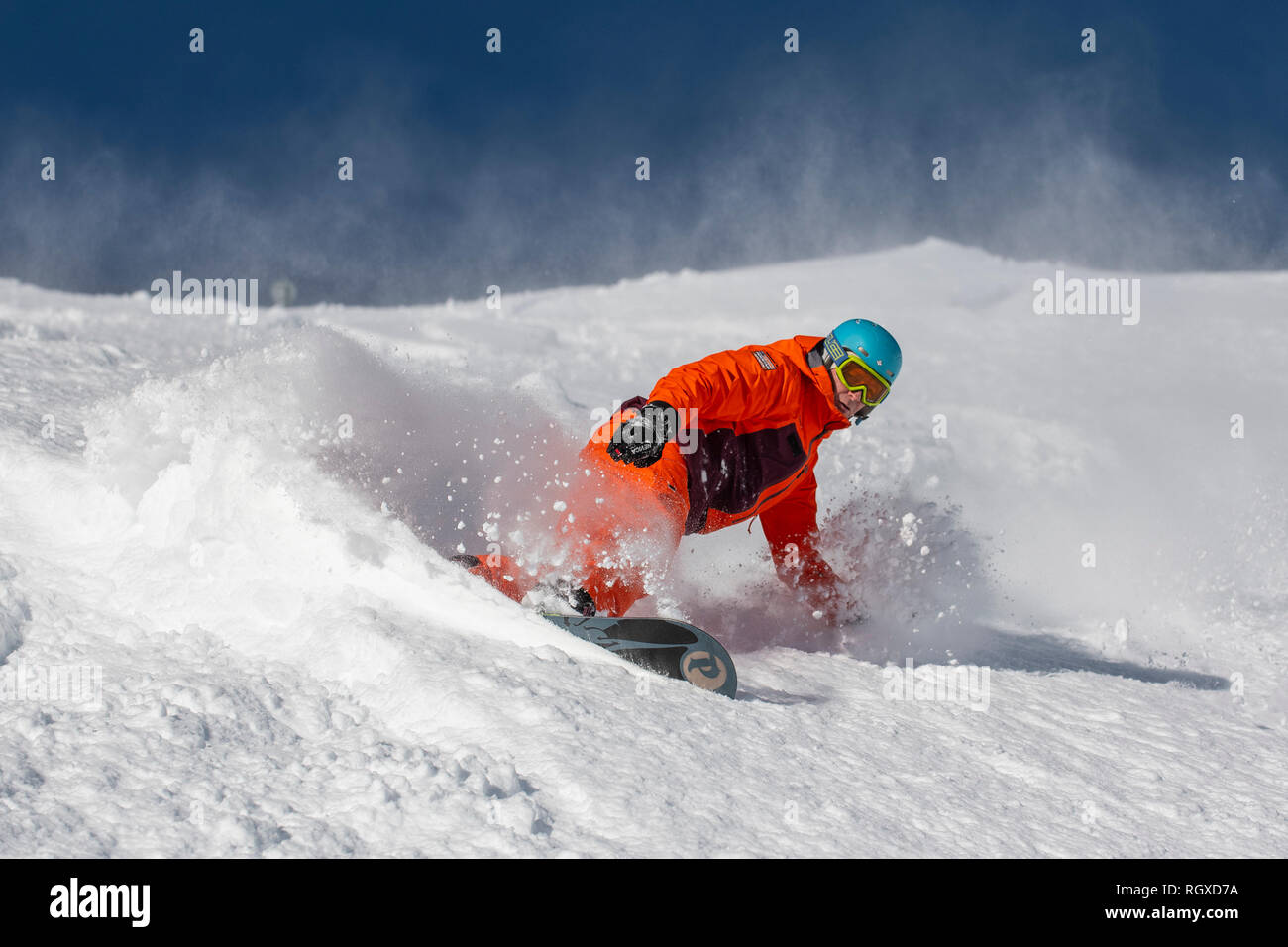 A man on a snowboard make s turn in deep powder snow in the ski resort of Courchevel in the France Alps. Stock Photo