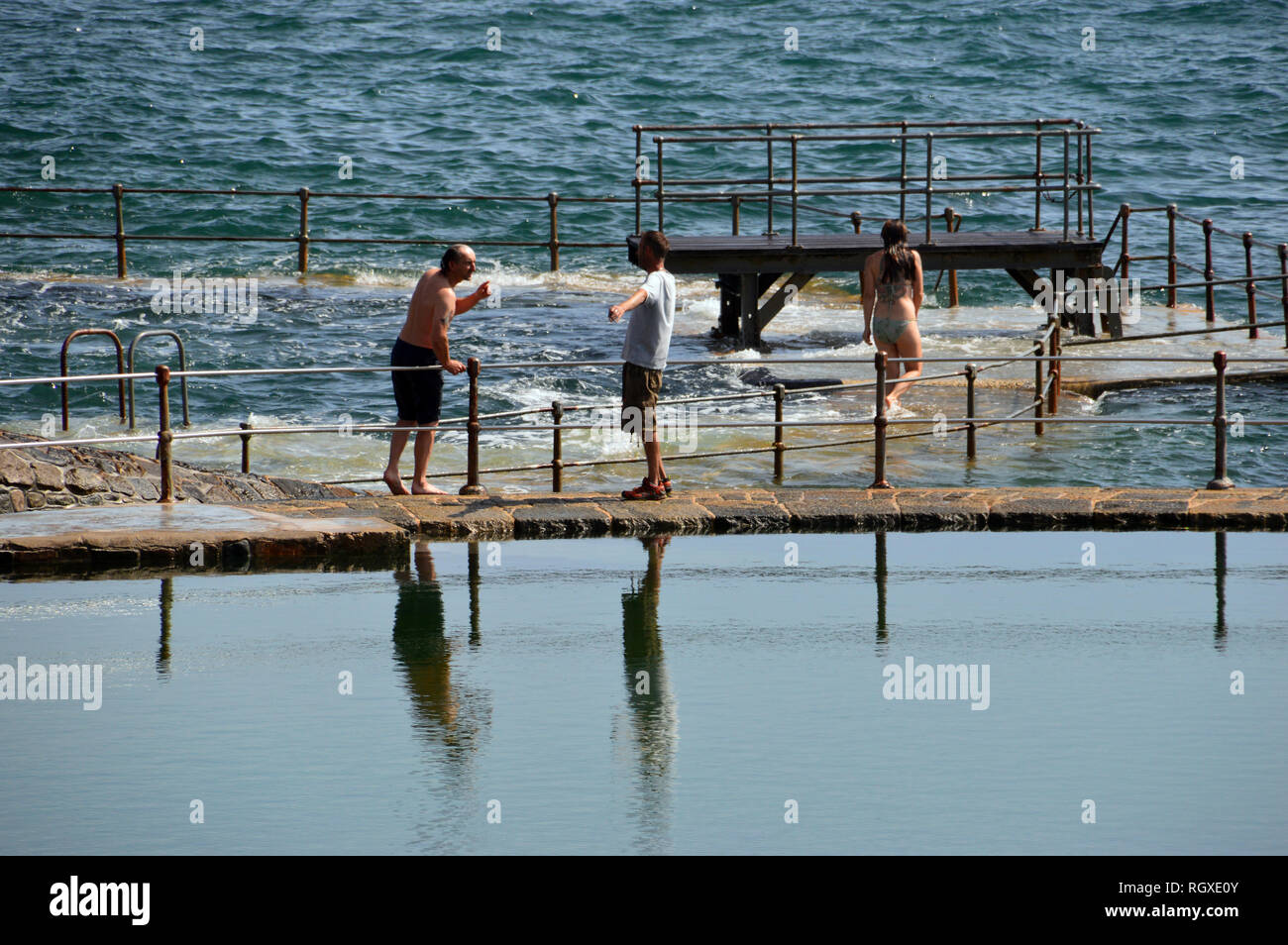 Two Men Talking by the Outdoor Swimming Pool in Havelet Bay, St Peter Port, Guernsey, Channel Islands.UK. Stock Photo