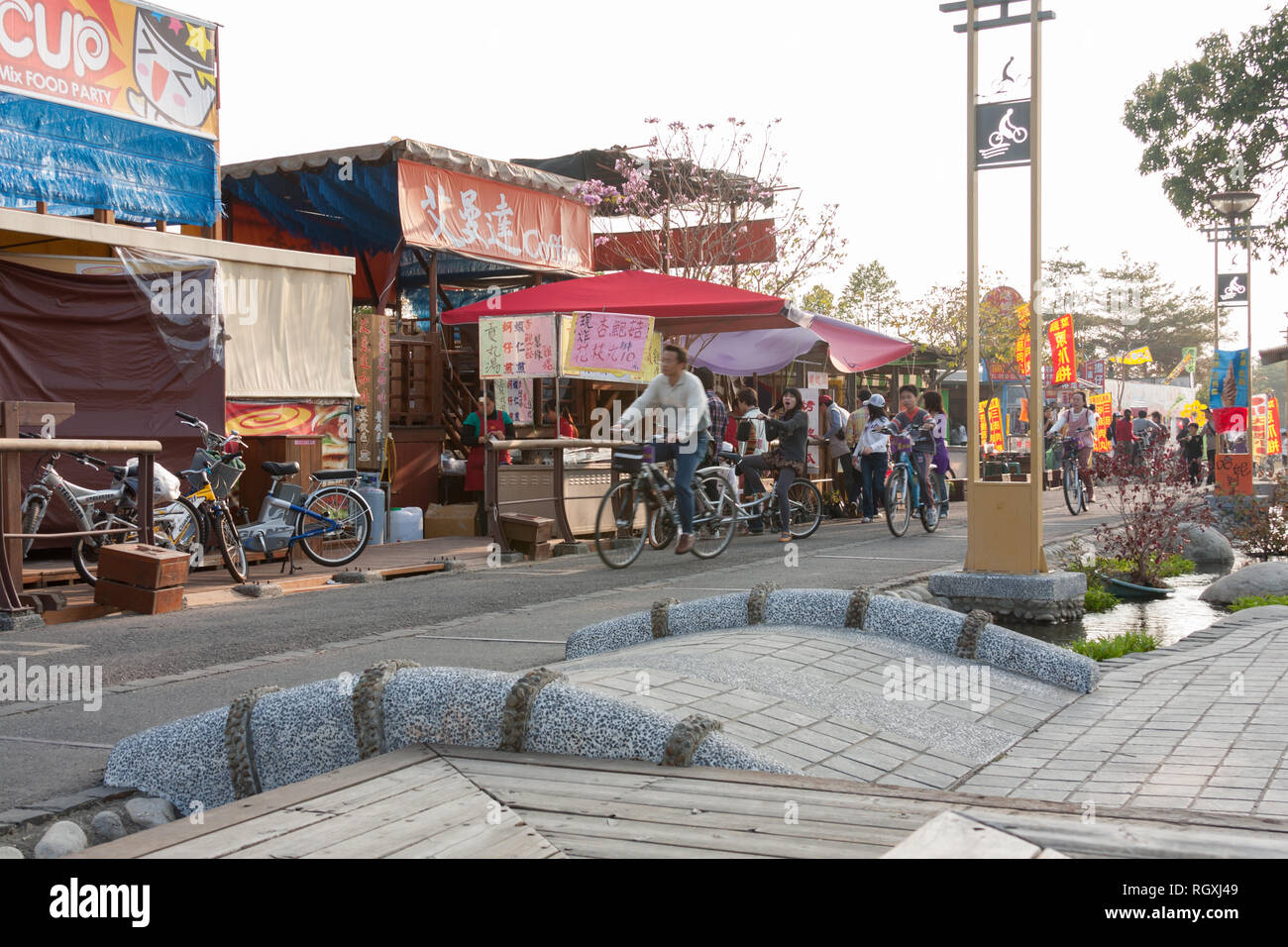 People ride past food and drink stalls, Hou-Feng Bikeway biking trail, Fengyuan District, Taichung City, Taiwan. Cycling infrastructure, leisure Stock Photo