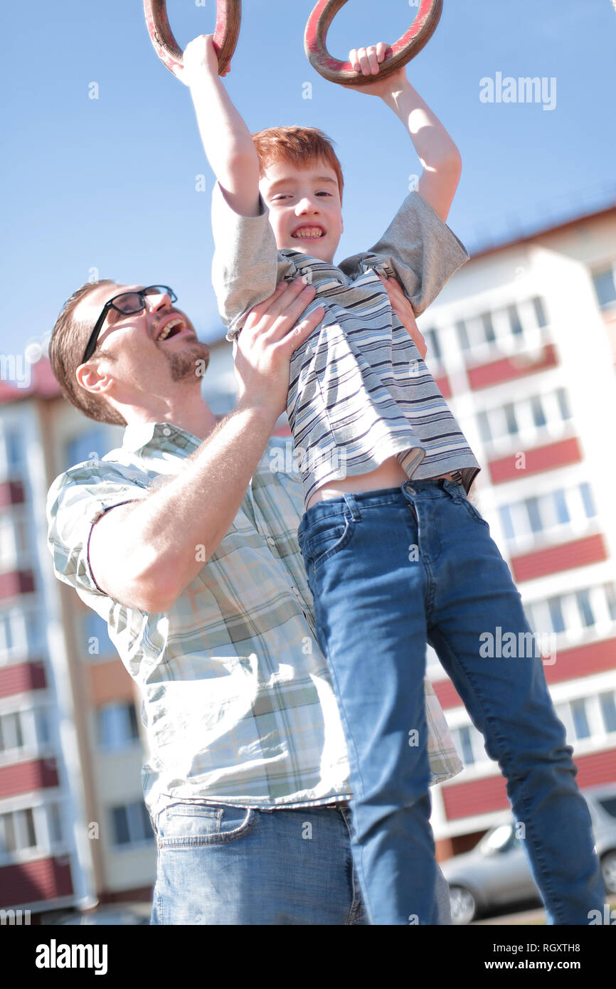 father helps his son to catch up on the bar Stock Photo