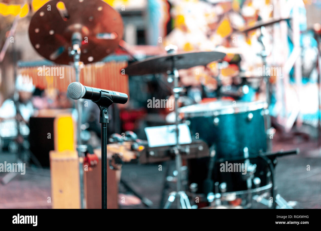 Microphone with drums and other musical instruments on a outdoor stage for performing music. Focus on microphone, blurred background Stock Photo