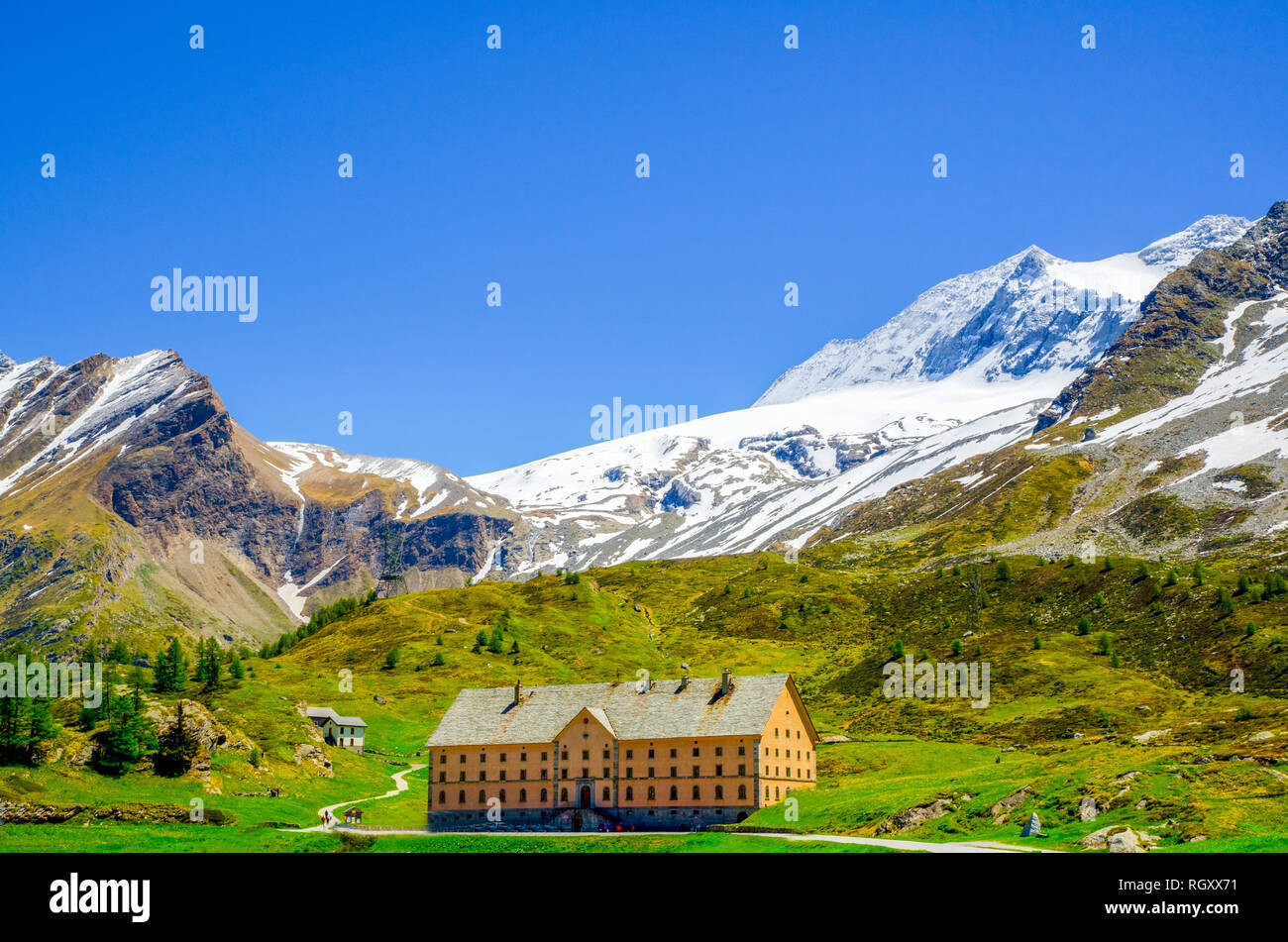 Big Building with Snow-capped Mountain and Blue Sky in Simplon Pass in Summer in Valais, Switzerland. Stock Photo