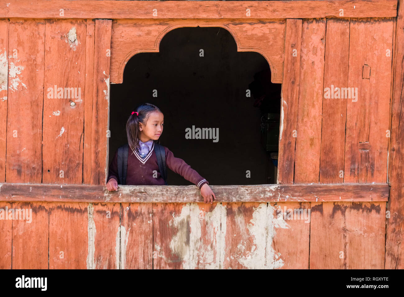 School girl looking out of a wooden window of a house in the town in Kali Gandaki valley Stock Photo