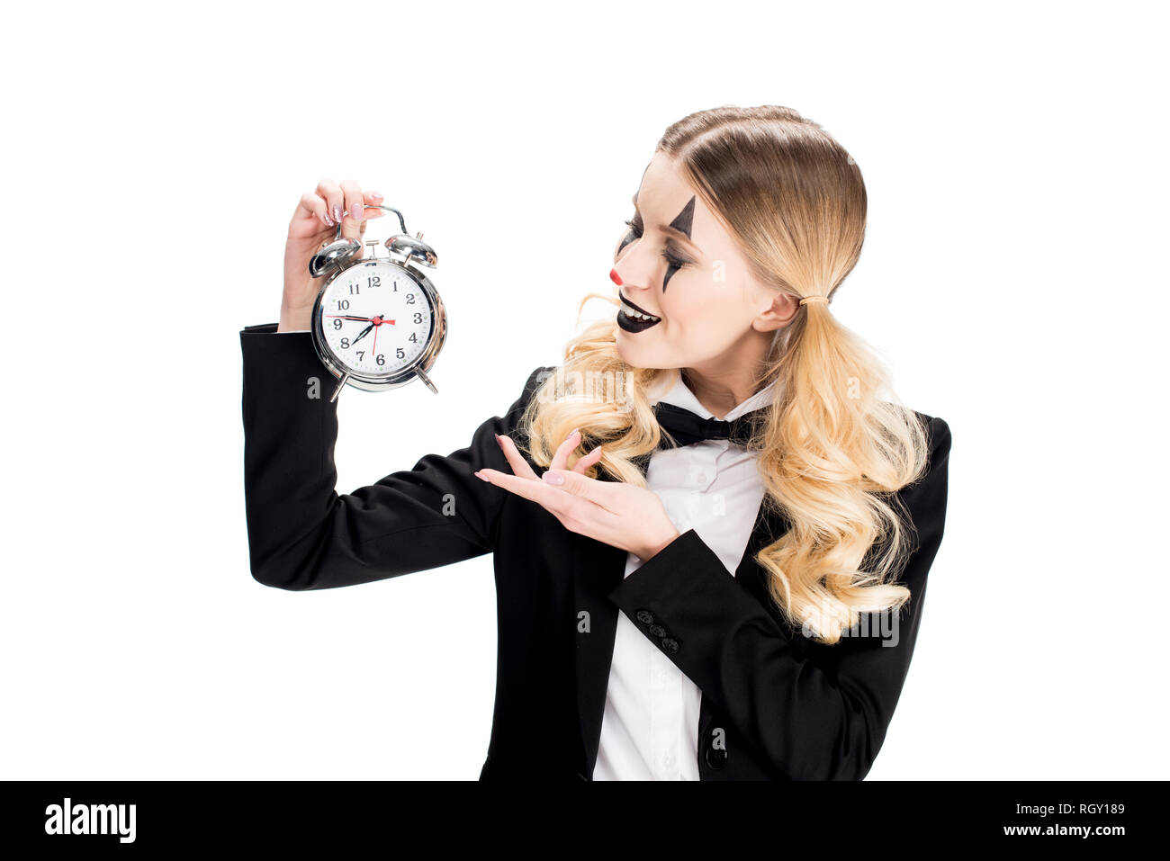 cheerful female clown looking at alarm clock isolated on white Stock