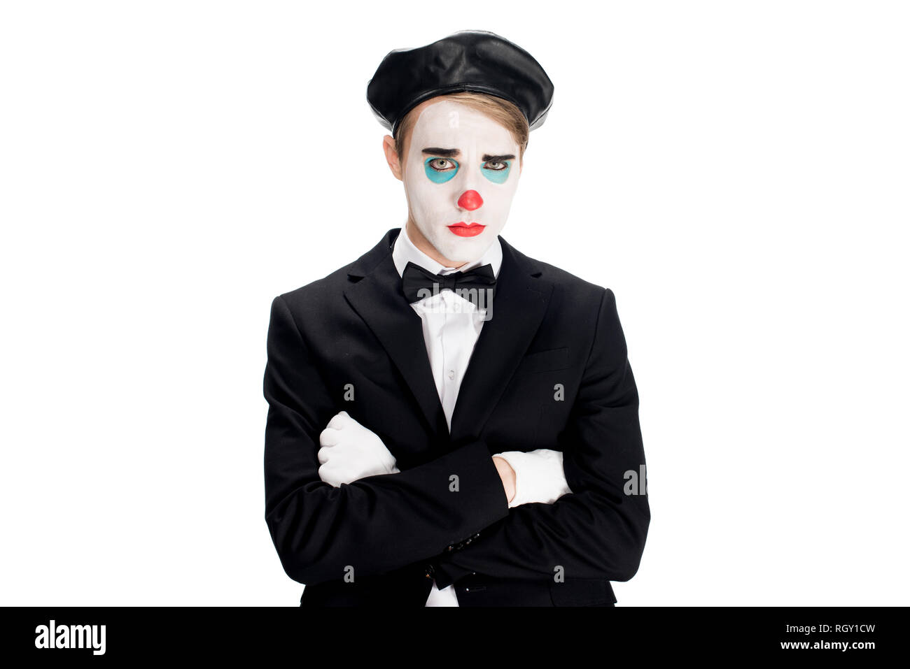 upset clown in suit and black beret standing with crossed arms isolated on white Stock Photo