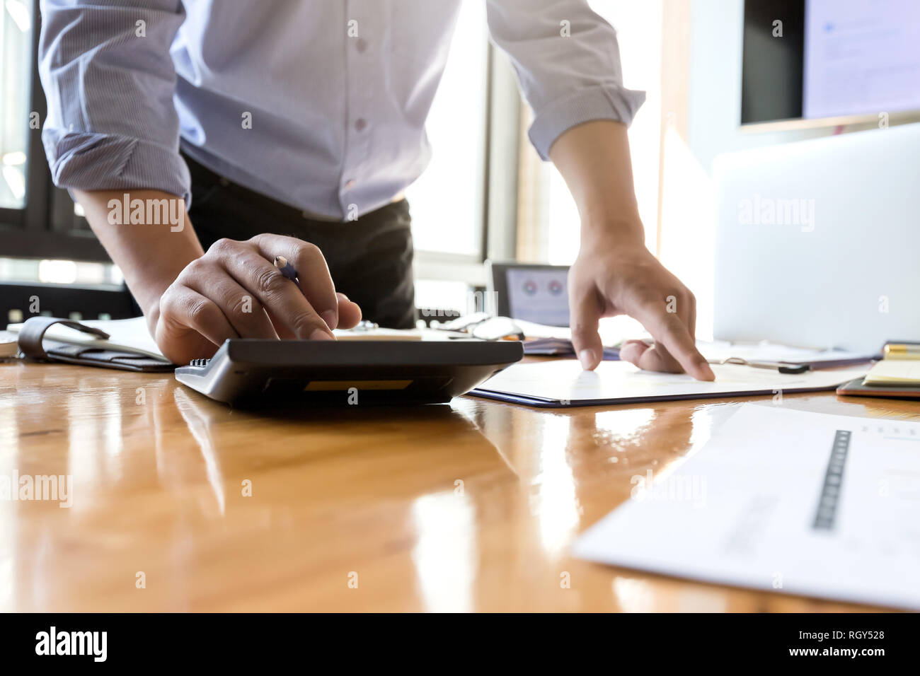 Businessman's hands using calculator and Financial data analyzing on wooden desk at the office Stock Photo