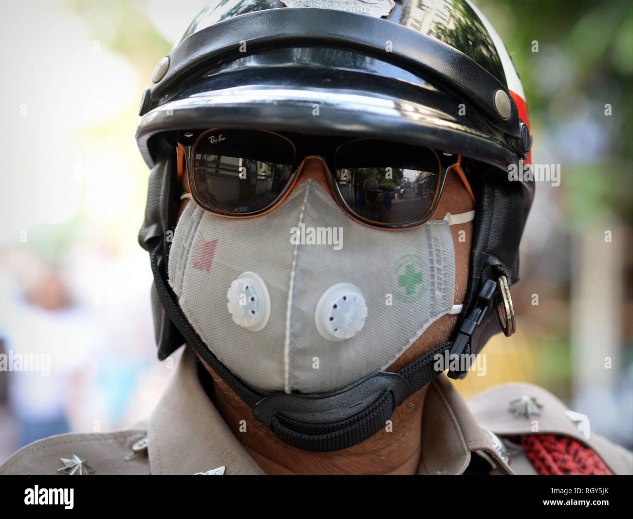 Royal Thai motorcycle police officer wears mirrored sunglasses and a protective face mask in polluted Bangkok. Stock Photo