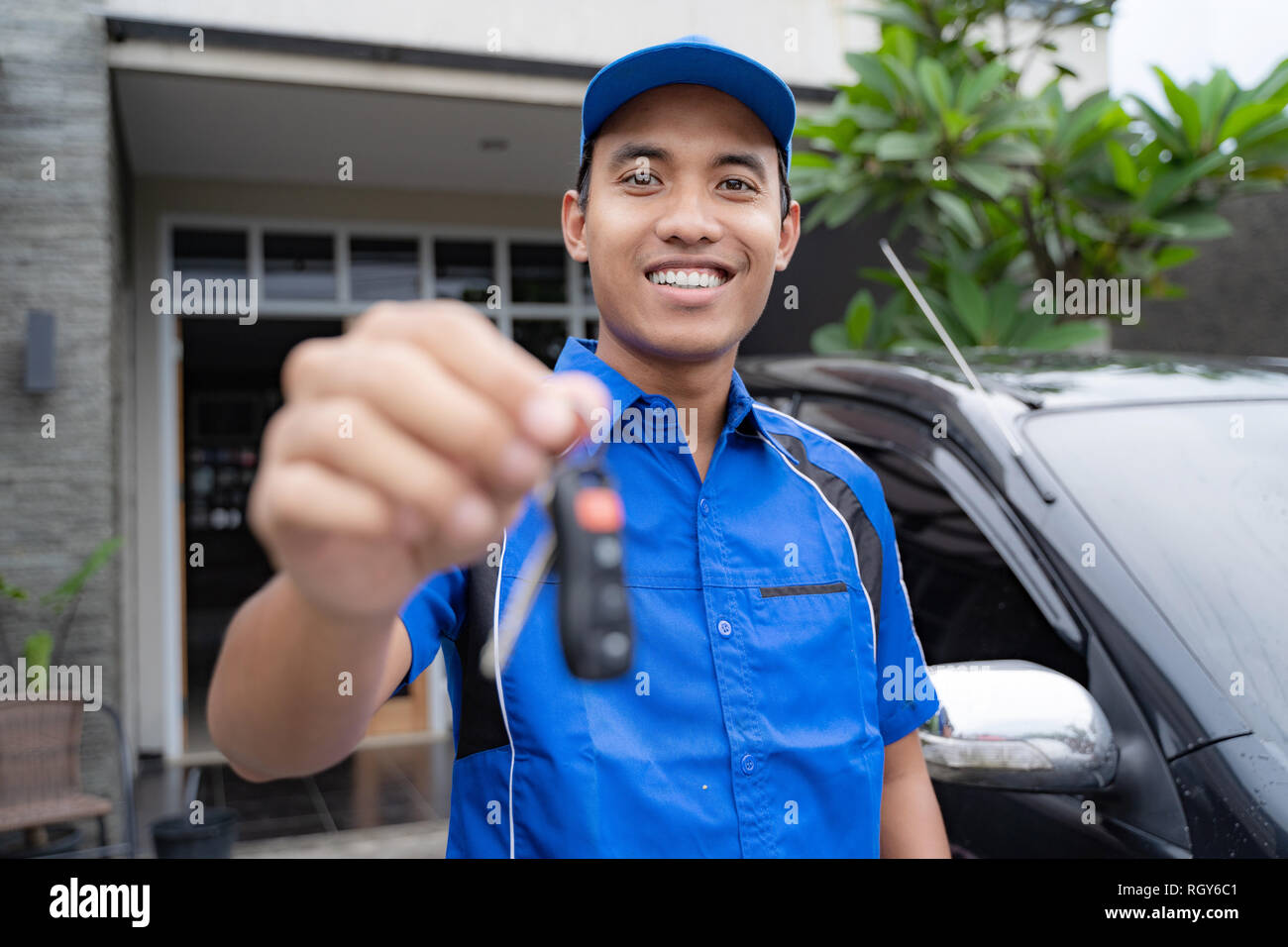 mechanic holding car key and smiling Stock Photo - Alamy