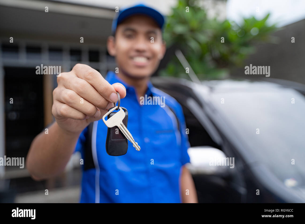 mechanic holding car key and smiling Stock Photo - Alamy
