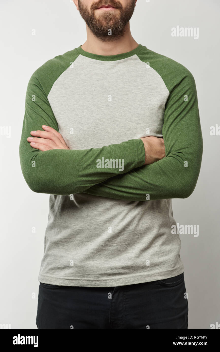 partial view of man with arms crossed in raglan sleeve baseball shirt with copy space isolated on grey Stock Photo