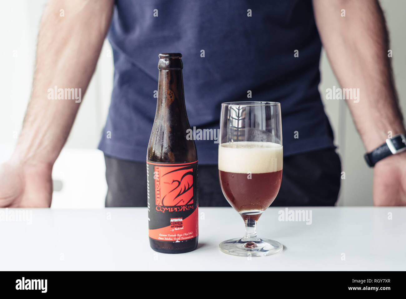 Madrid, Spain - November 10, 2018: Man serving craft beer from bottle in glass cup. Stock Photo