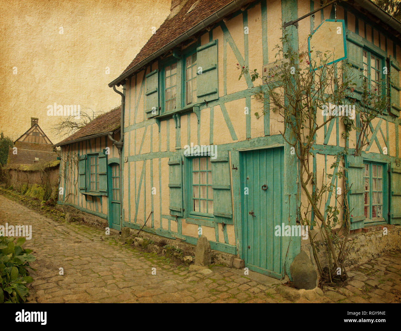 Gerberoy.  Old house in medieval village. Gerberoy is a commune in the Oise department in northern France.  Photo in retro style. Paper texture. Stock Photo