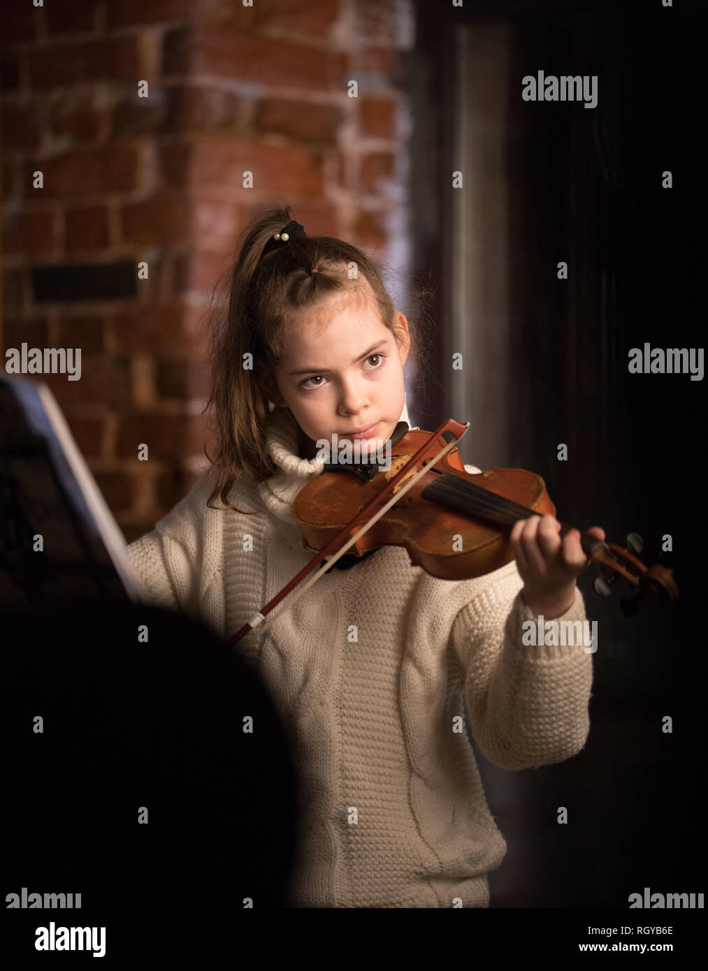 A little beautiful girl in sweater playing violin Stock Photo - Alamy