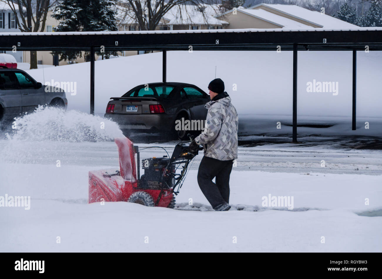 Extreme winter weather! A teenage boy clearing snow from a sidewalk with a mechanical snow blower after a winter storm in Michigan, USA. Stock Photo