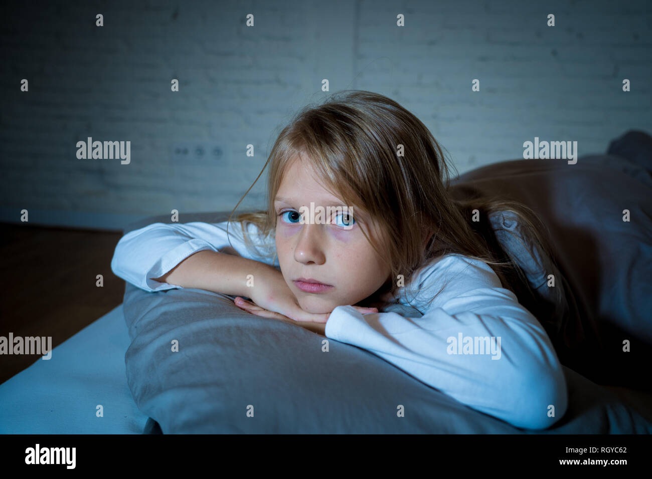 Cute little caucasian girl lying in bed covering her head with blanket
