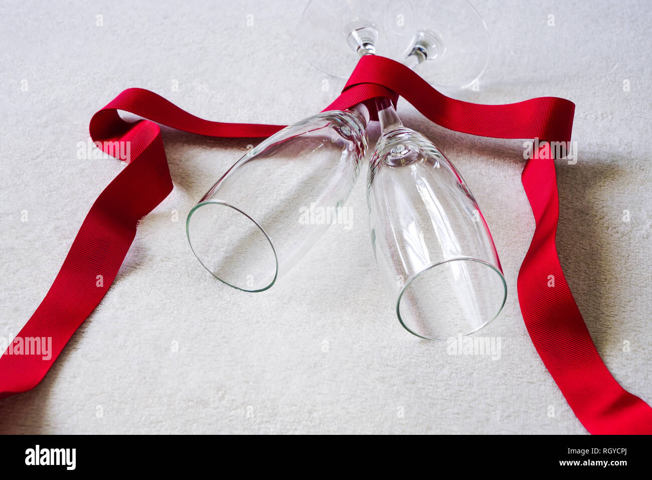 Champagne flutes wrapped in red ribbon in a fluffy white background. Concept of Valentine's Day or romantic celebration. Stock Photo