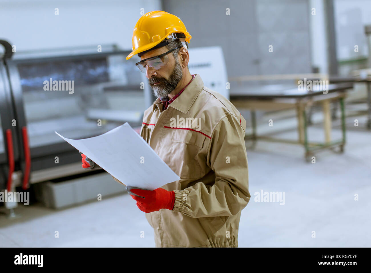 Handsome mature engineer looking at a plan in the factory Stock Photo