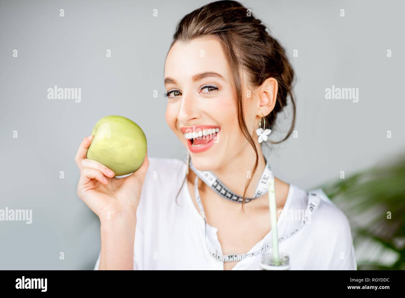 Portrait of a young woman with apple indoors. Healthy eating and wight loss concept Stock Photo