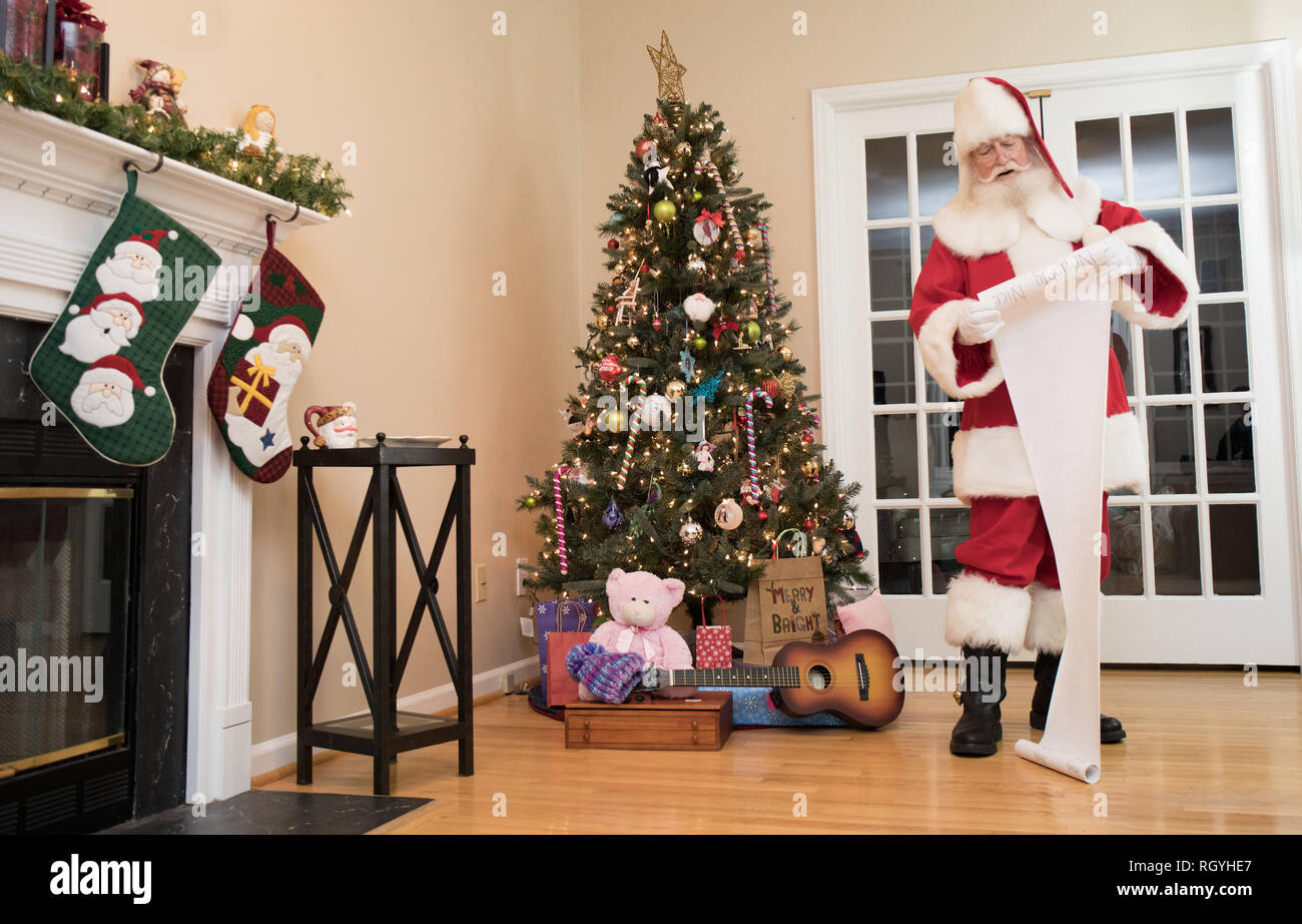 Santa reading his naughty or nice list in a living room decorated for