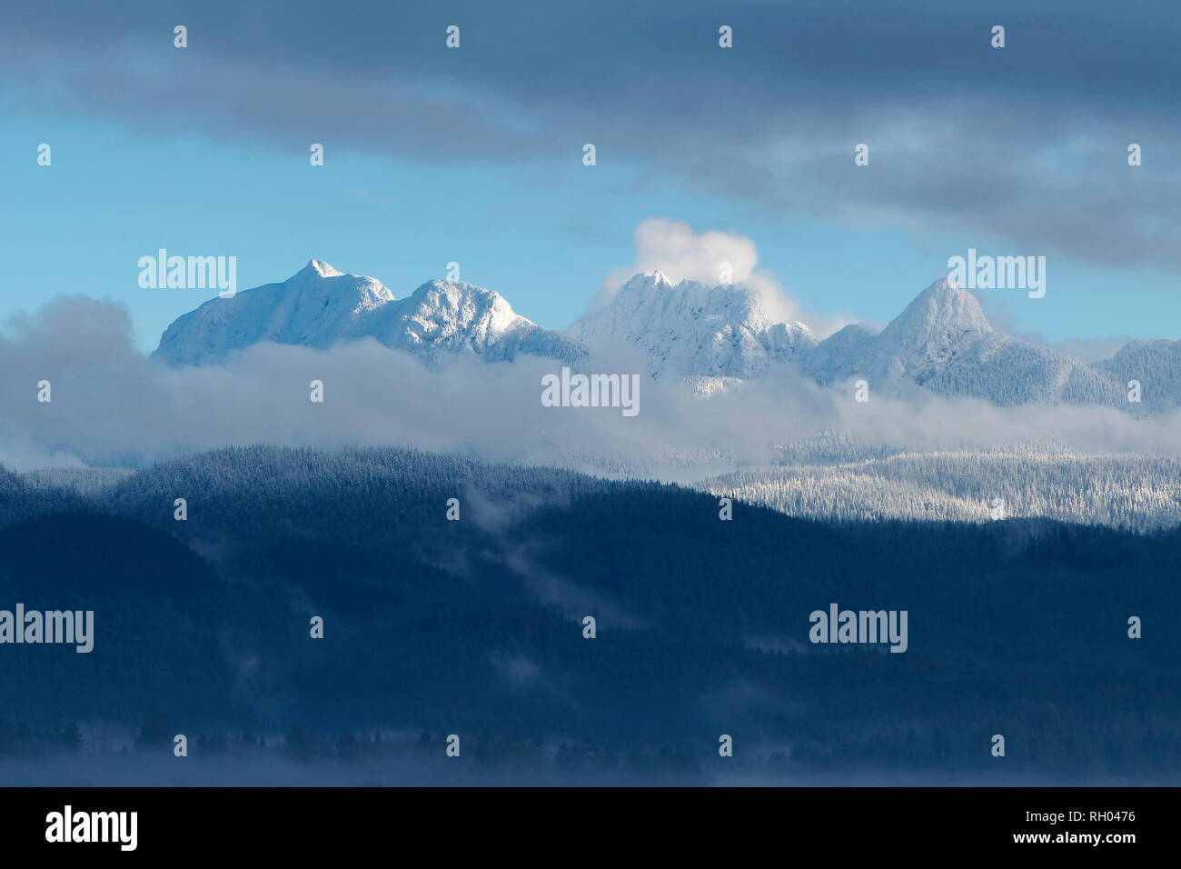 Golden Ears Mountain Range with snow-capped peaks and wispy clouds in the foreground. Stock Photo