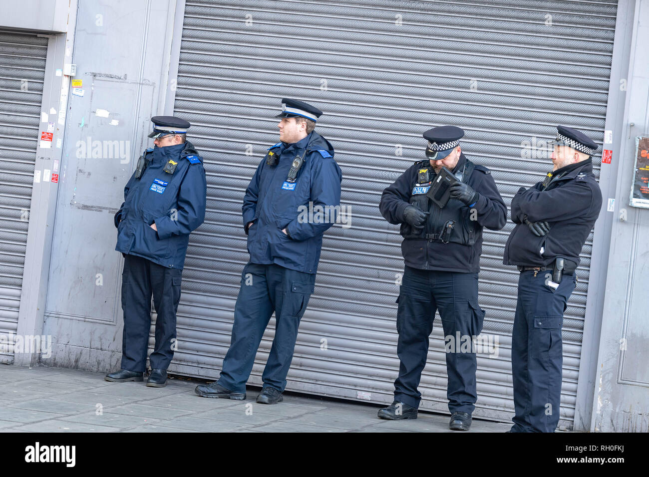 Romford, Essex, UK. 31st January 2019 Metropolitan Police trial live Facial recognition technology outside Romford Station. The police cameras scan passers by and check them against a 'watch list' in real time allowing them to apprehend any wanted people. A small number of protesters against the scheme protested outside Romford Station. Police officers wait for the face recogntion cameras to be triggered Credit: Ian Davidson/Alamy Live News Stock Photo