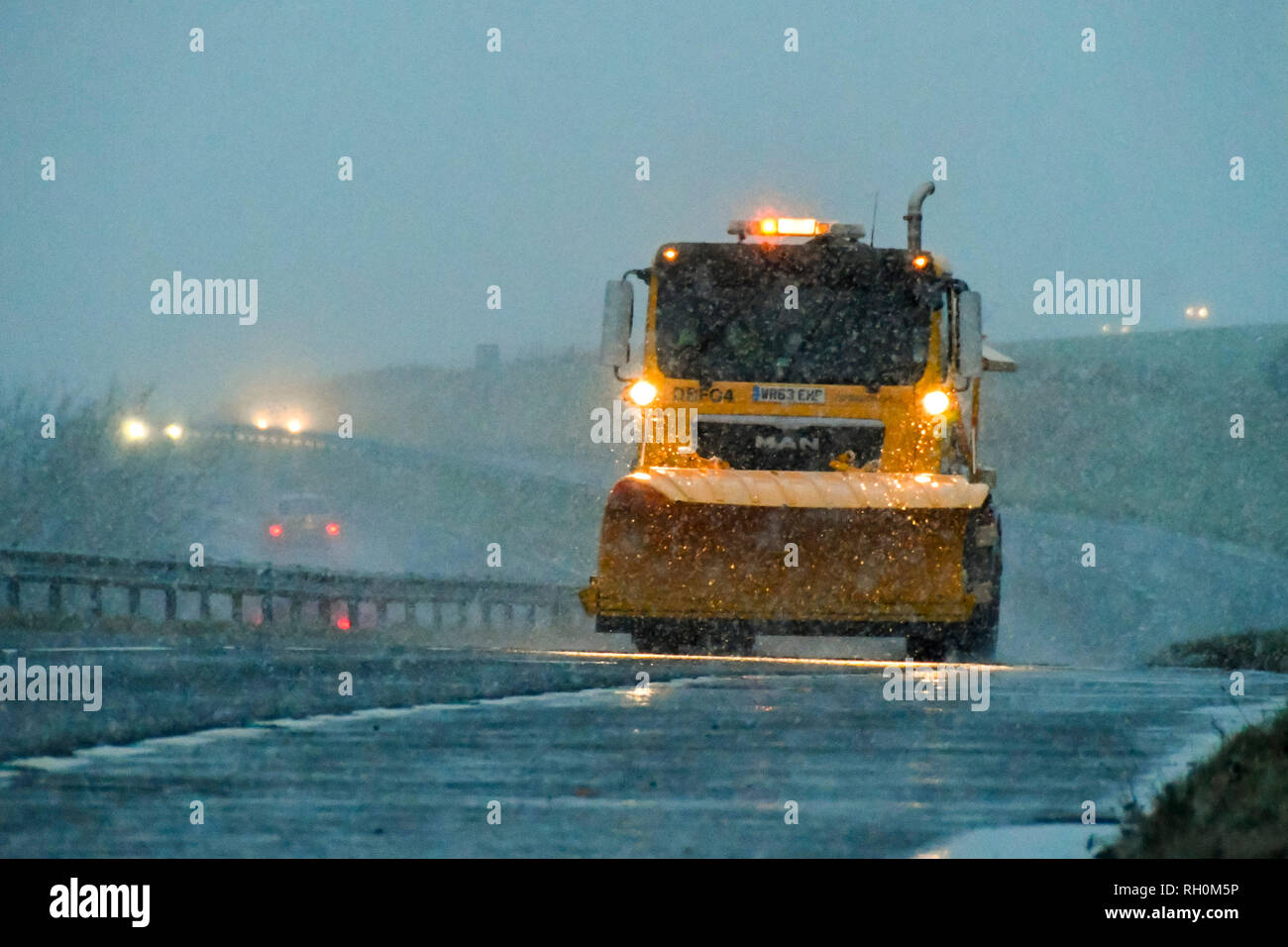 A35, Long Bredy, Dorset, UK.  31st January 2019. UK Weather.  A gritting lorry with a snow plough fitted treating the road with salt as snow falls at dusk.  An Amber weather warning has been issued for the South West of England with 5-10cm of snow predicted to fall.  Picture Credit: Graham Hunt Photography/Alamy Live News Stock Photo