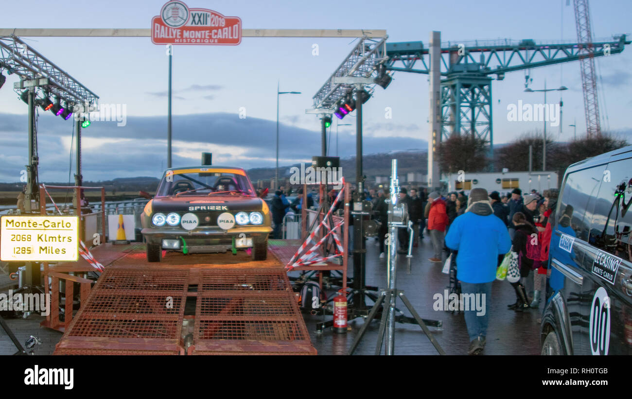 Clydebank, Scotland, UK. 30th January, 2019. The 22nd Rallye Monte-Carlo Historique (Monte Carlo Rally Historical) has set off from Queens' Quay, Clydebank, West Dunbartonshire. It was the second time the town had hosted the event, the last time being 2012. Crowds turned out to view the dozens of vintage cars parked beside the iconic Titan Crane. As evening fell, Bailie Denis Agnew of West Dunbartonshire Council raised the Scottish flag, the Saltire, to mark the start. 17 of the classic cars will travel some 1,285 miles (2,068 kilometres). Iain McGuinness / Alamy Live News Stock Photo
