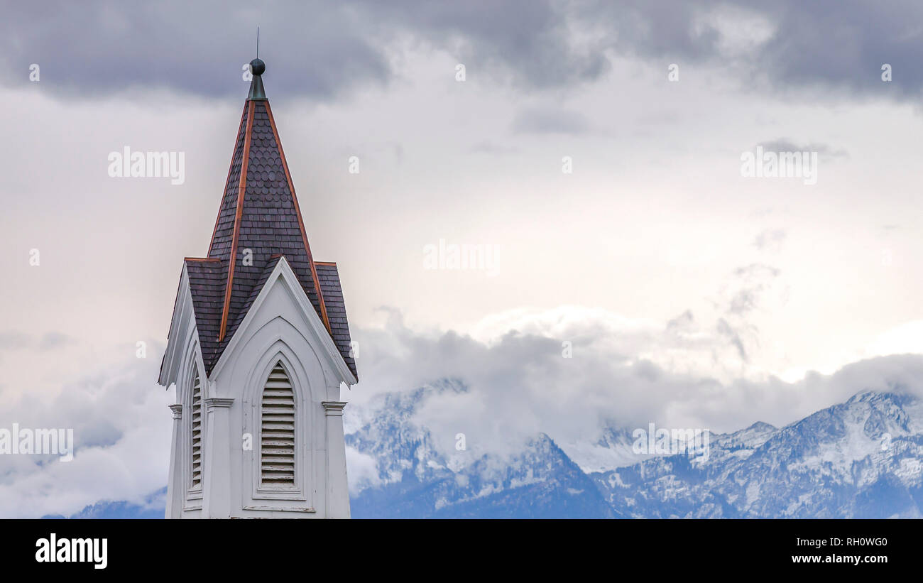 Church steeple with mountain and clouds background Stock Photo