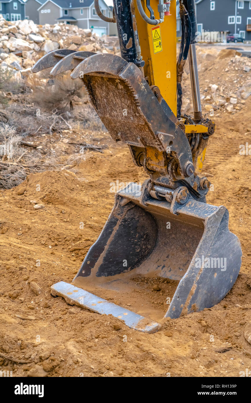 Excavator arm and bucket against rocks and homes Stock Photo Alamy
