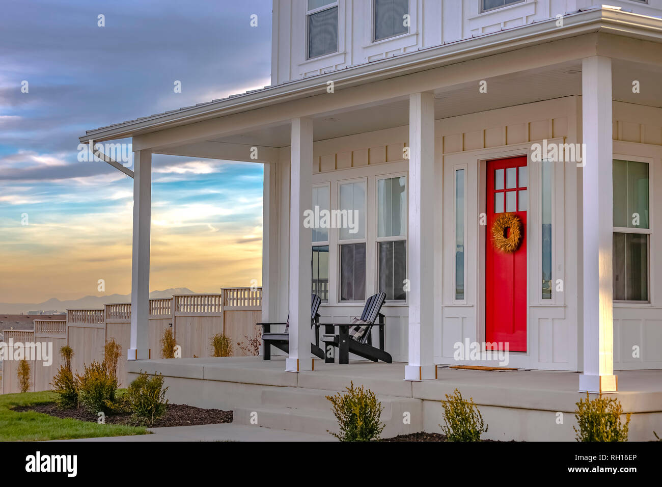 Facade Of Home With Red Door Porch Stairs And Yard Stock Photo