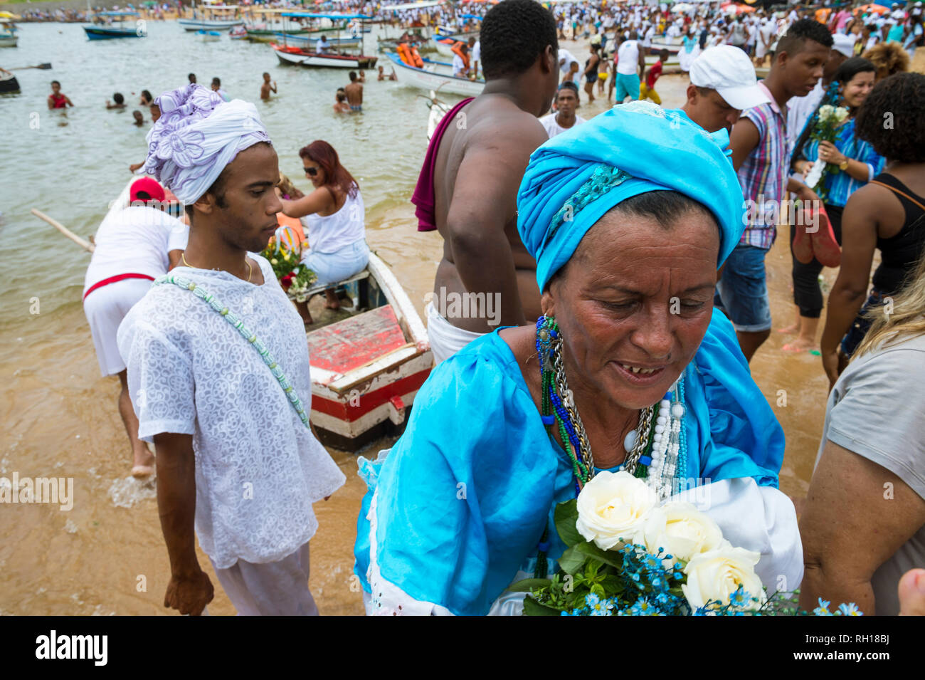 SALVADOR, BRAZIL - FEBRUARY 2, 2016: Celebrants at the Festival of Yemanja carry flowers on Rio Vermelho beach to leave as an offering at sea. Stock Photo