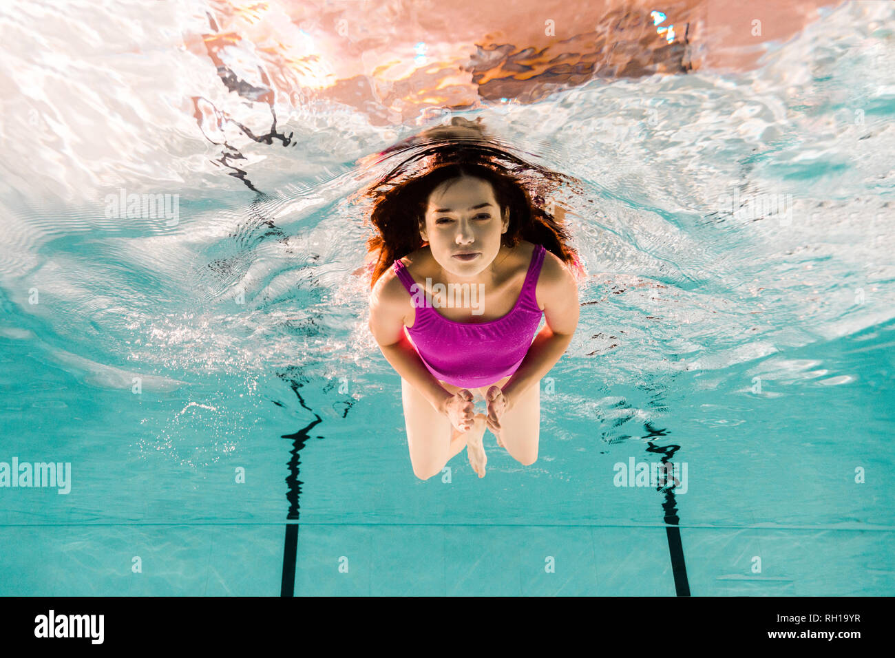 beautiful woman diving underwater in swimsuit in swimming pool Stock