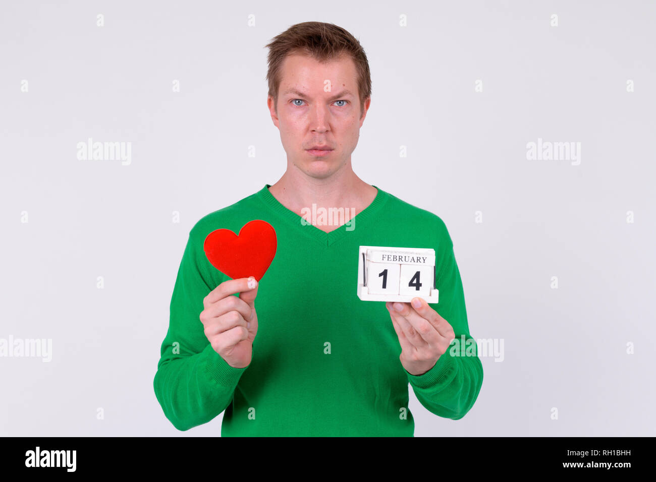 Young handsome man holding calendar block and heart ready for Valentine's day Stock Photo