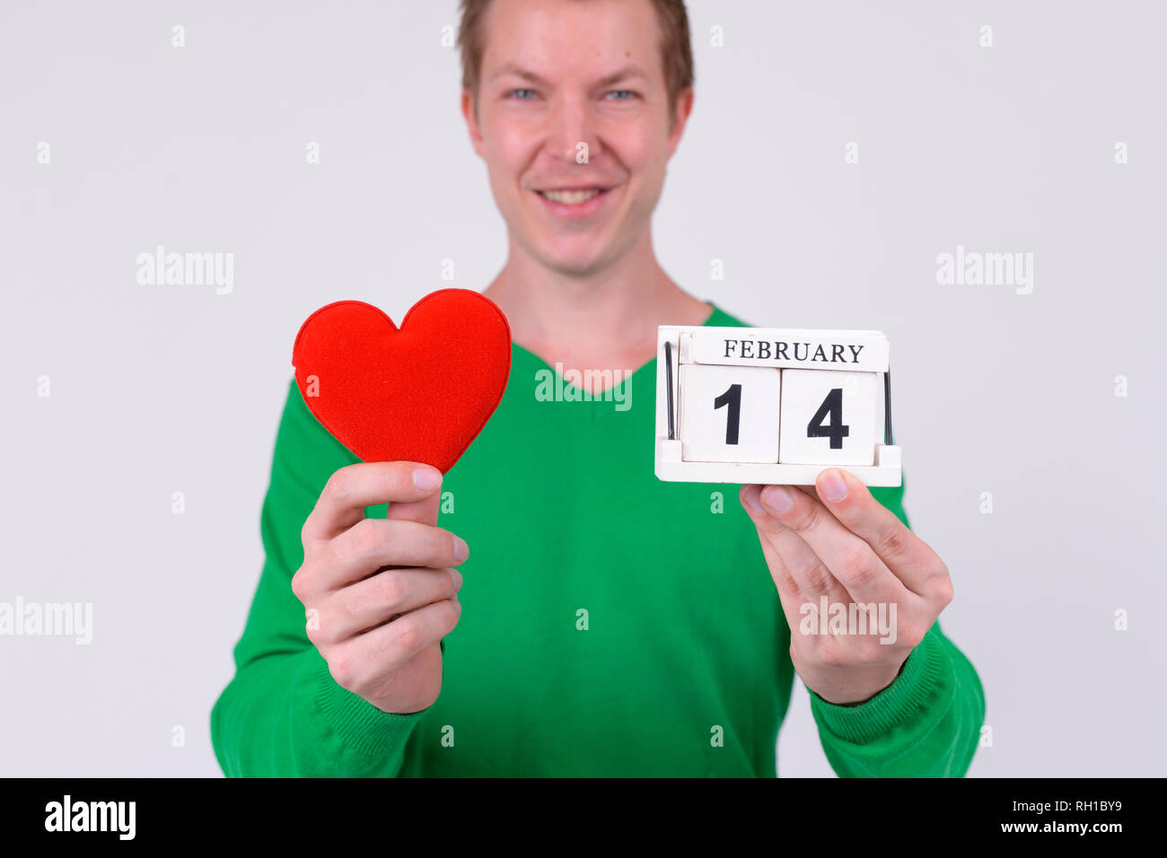 Happy young man holding calendar block and heart ready for Valentine's day Stock Photo