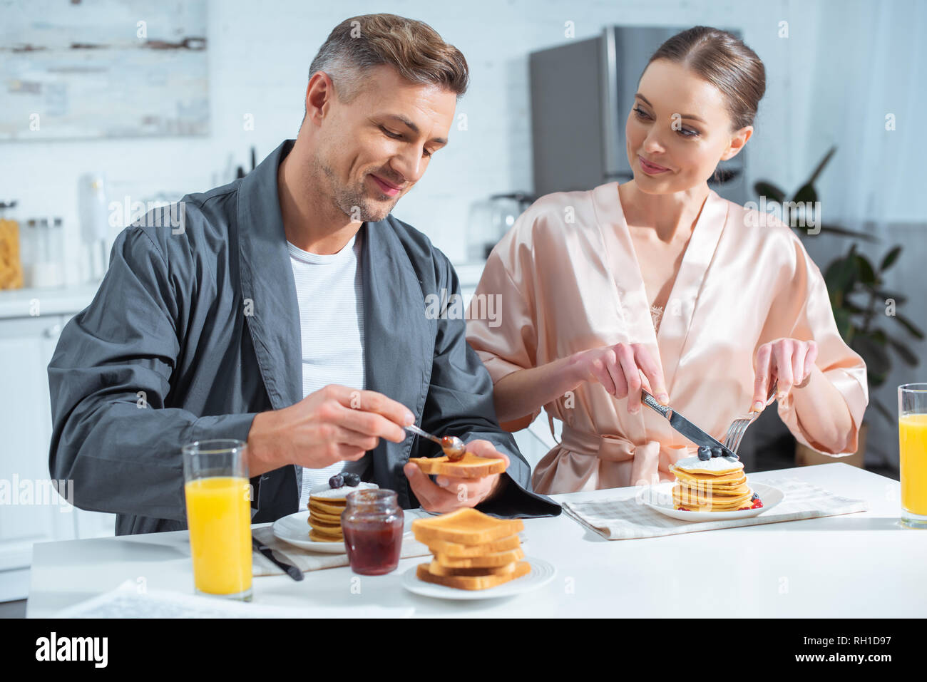 Breakfast In Robe selective focus of husband and wife in robes during breakfast with ...