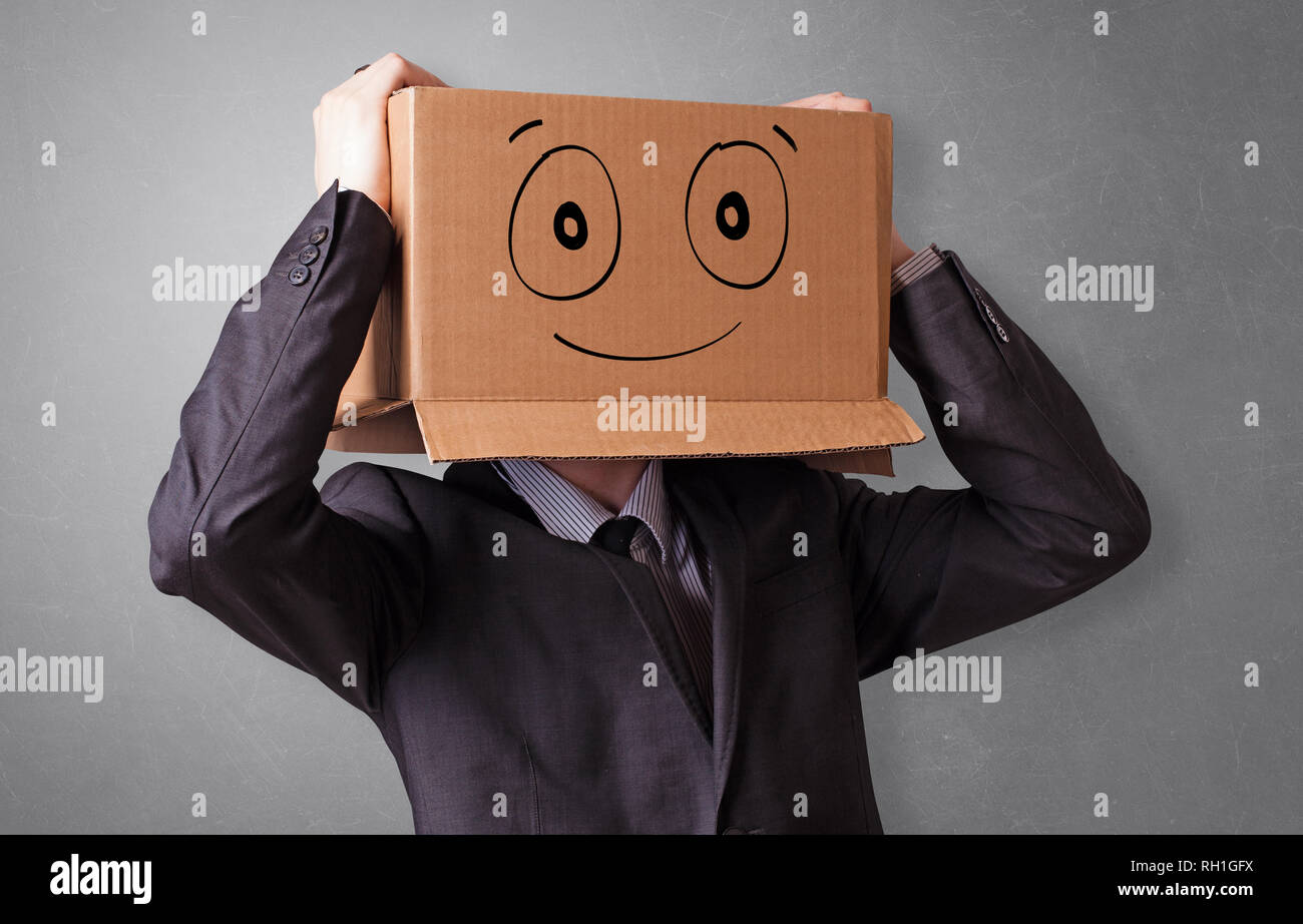 Young man standing and gesturing with a cardboard box on his head with ...